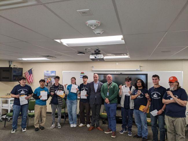 A group of people standing in a classroom holding certificates.